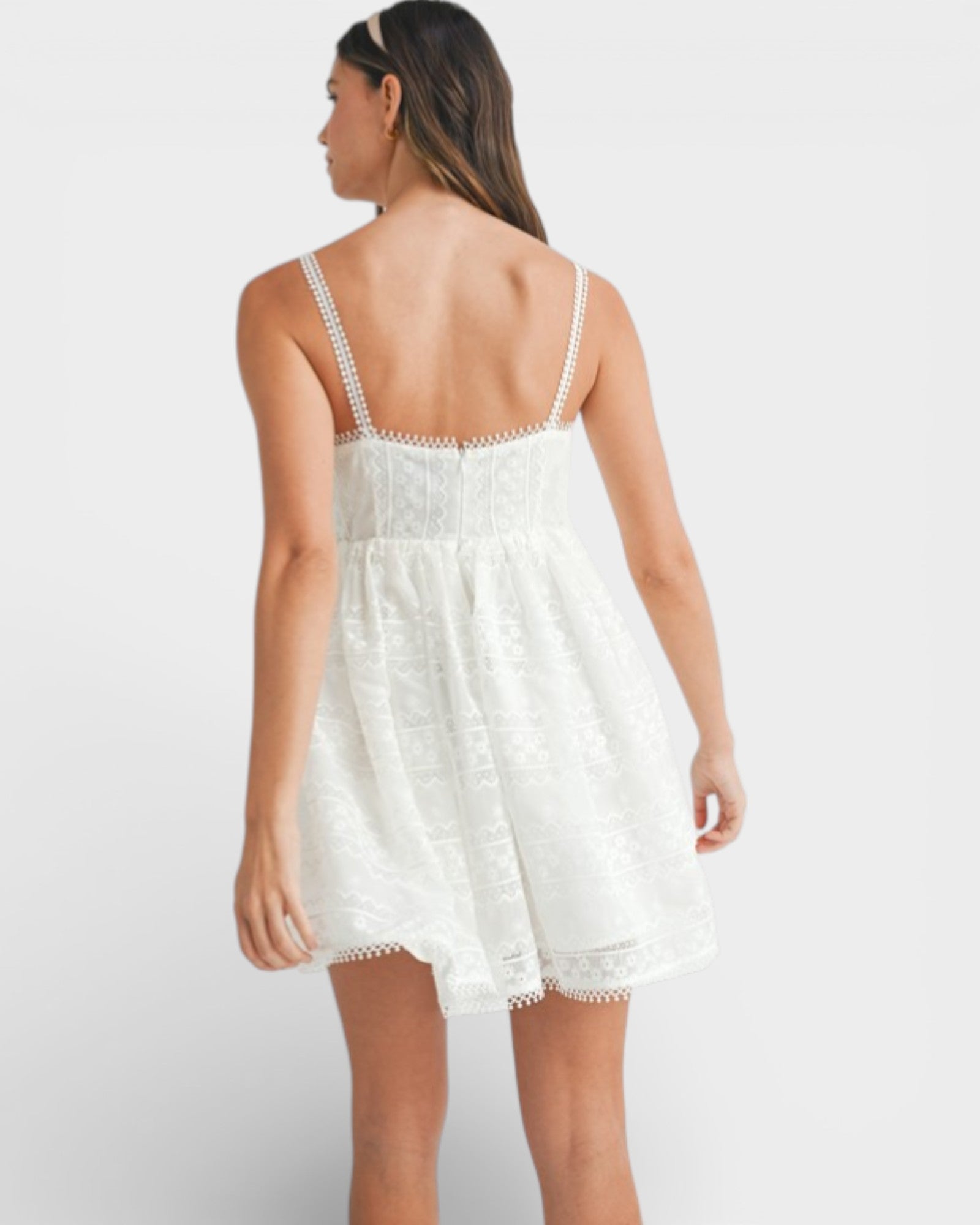 Woman wearing a white lace dress against a plain background