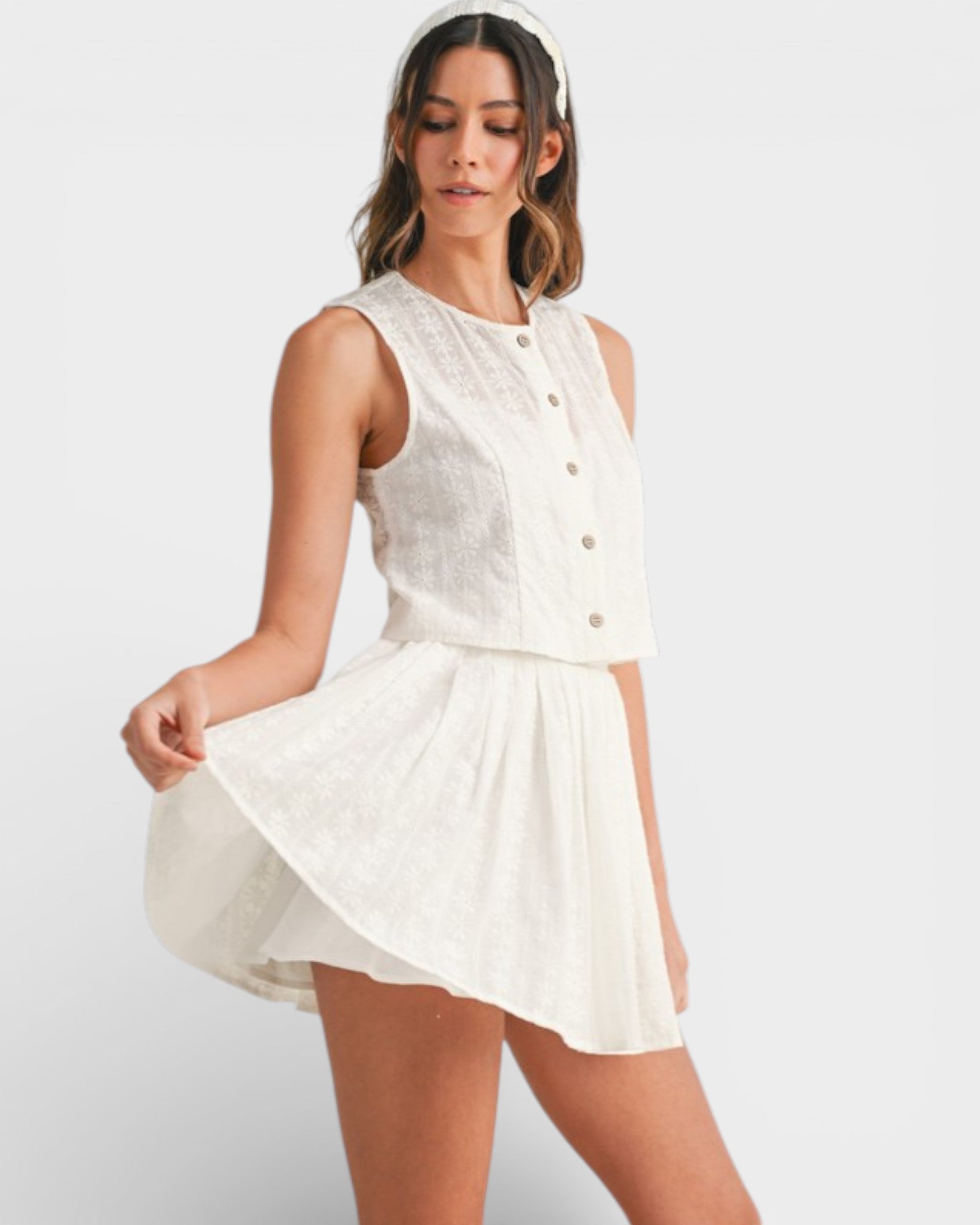 Woman wearing a white sleeveless dress on a plain background