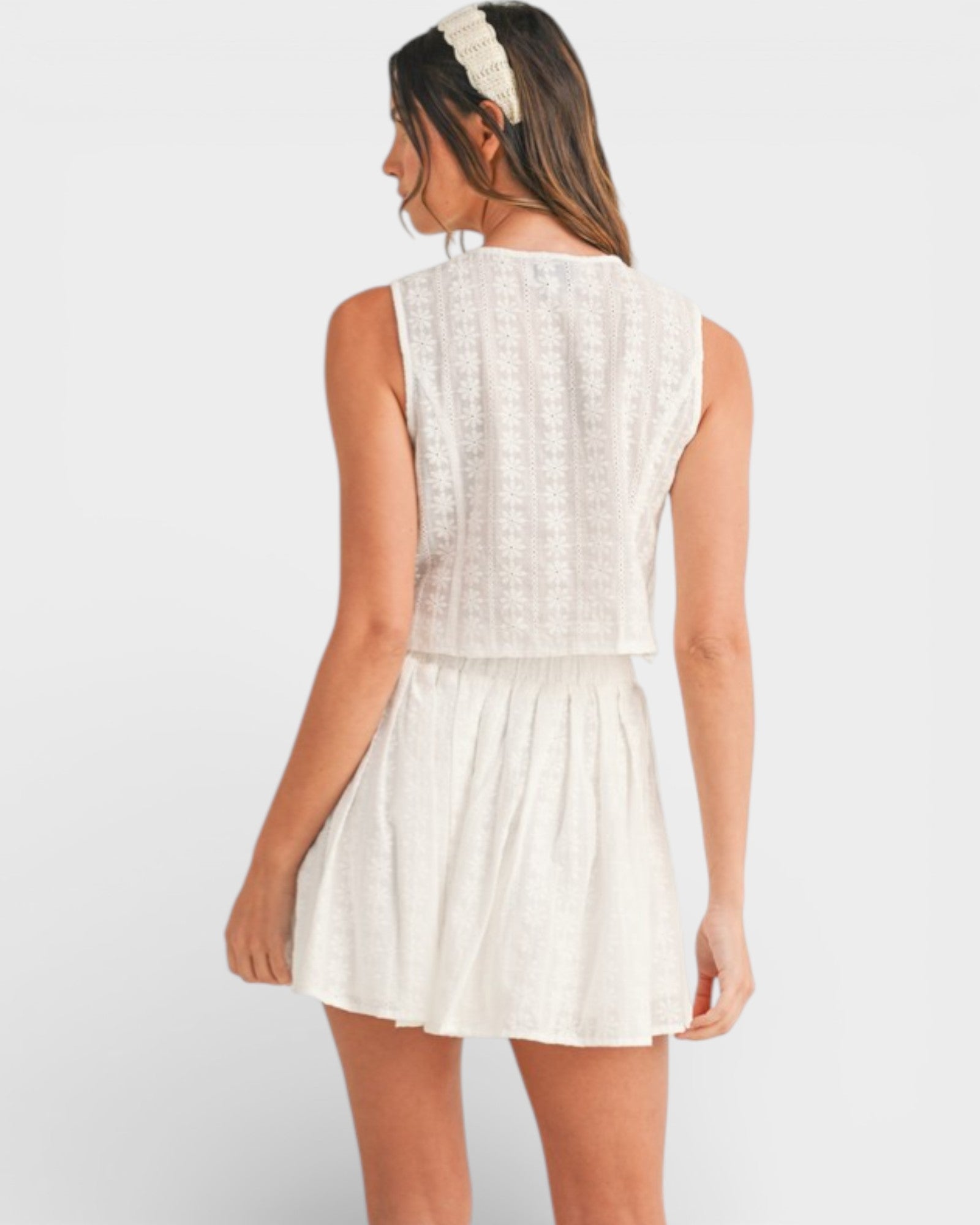 Woman wearing a white sleeveless dress on a plain background