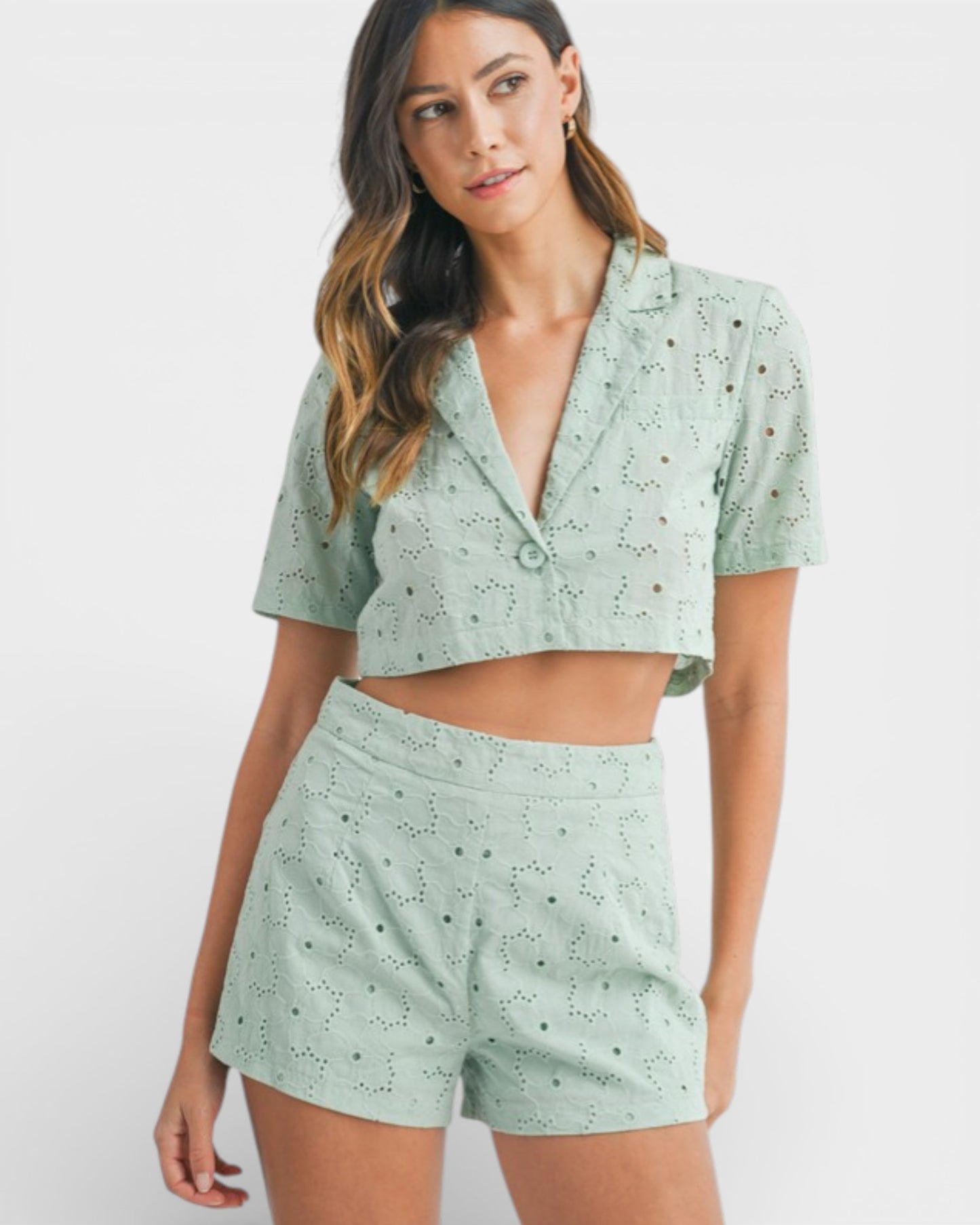 Woman wearing a matching green top and shorts set on a white background