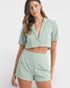 Woman wearing a matching green top and shorts set on a white background