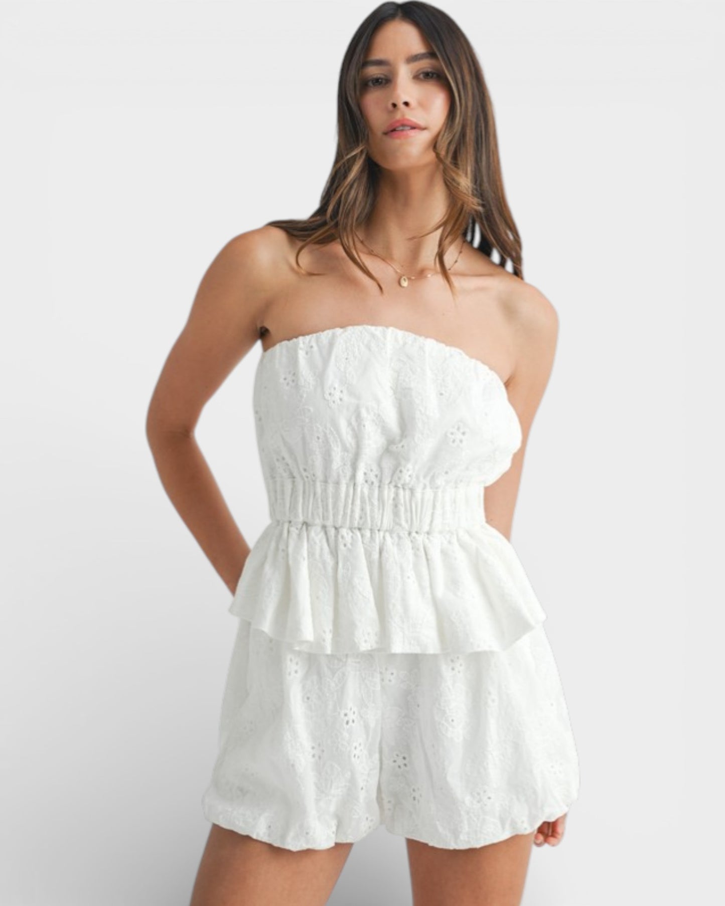 Woman wearing a white strapless dress against a plain background