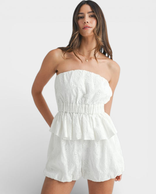 Woman wearing a white strapless dress against a plain background