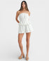Woman wearing a white strapless dress on a plain background