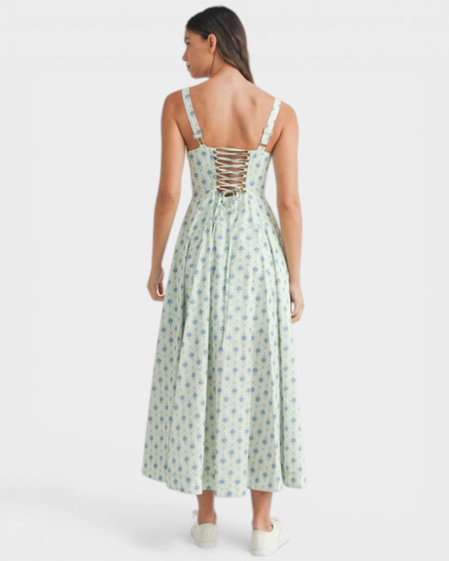 Woman wearing a green floral dress with a lace-up back on a white background
