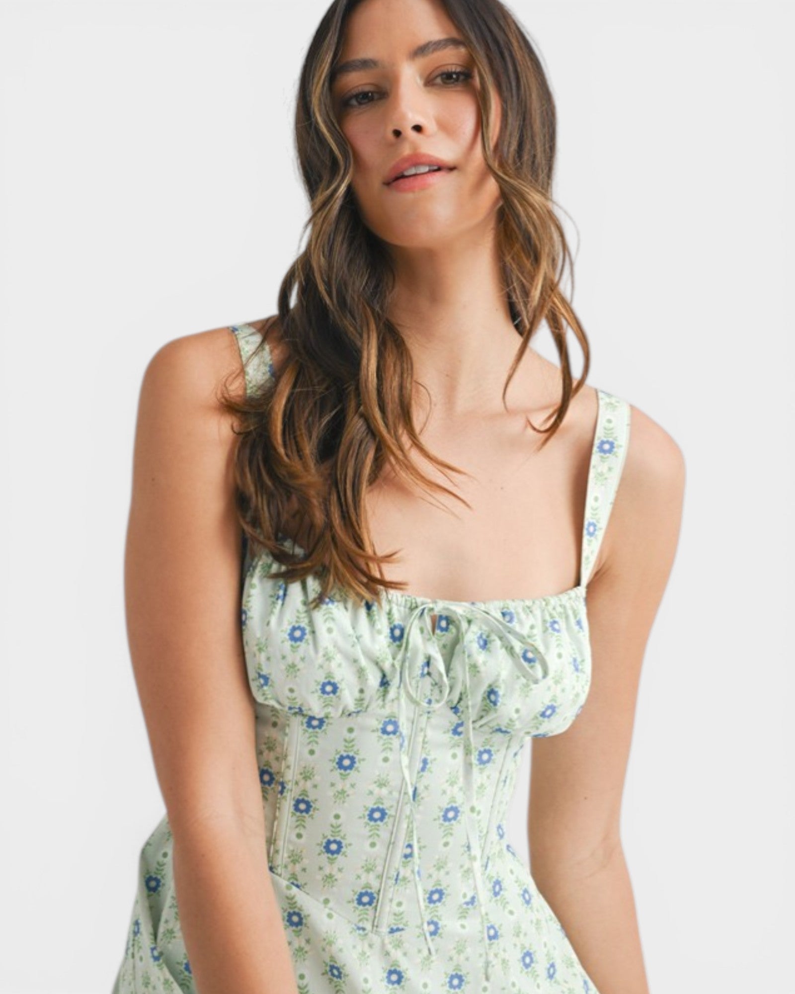 Woman wearing a green floral dress against a white background