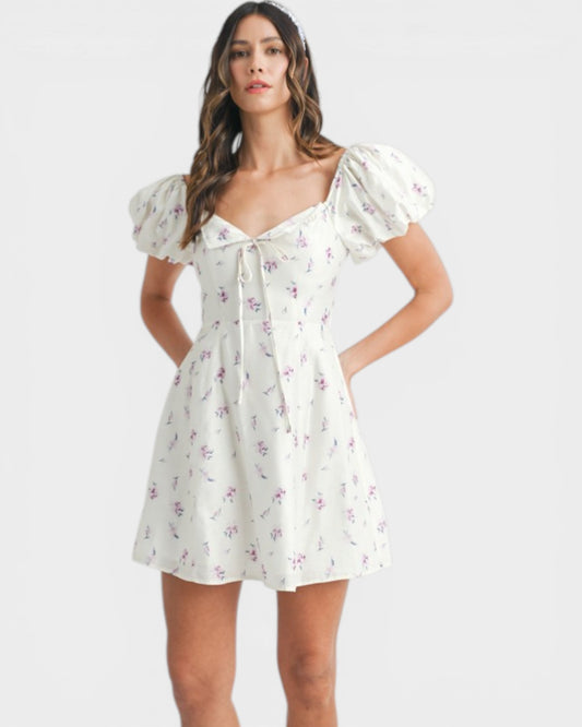 Woman wearing a white floral dress on a plain background