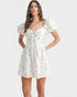 Woman wearing a white floral dress on a plain background