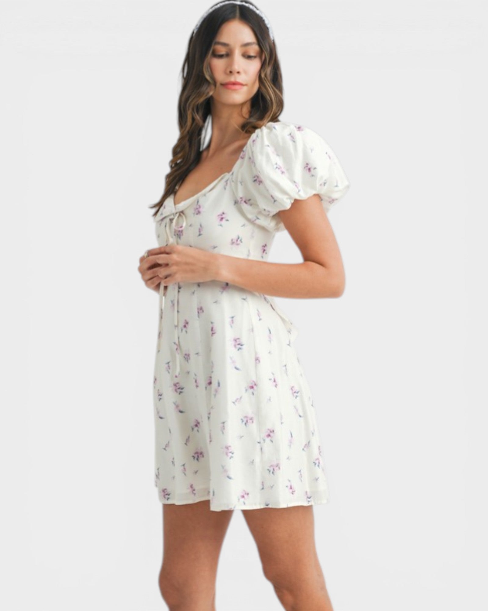 Woman wearing a white floral dress on a plain background