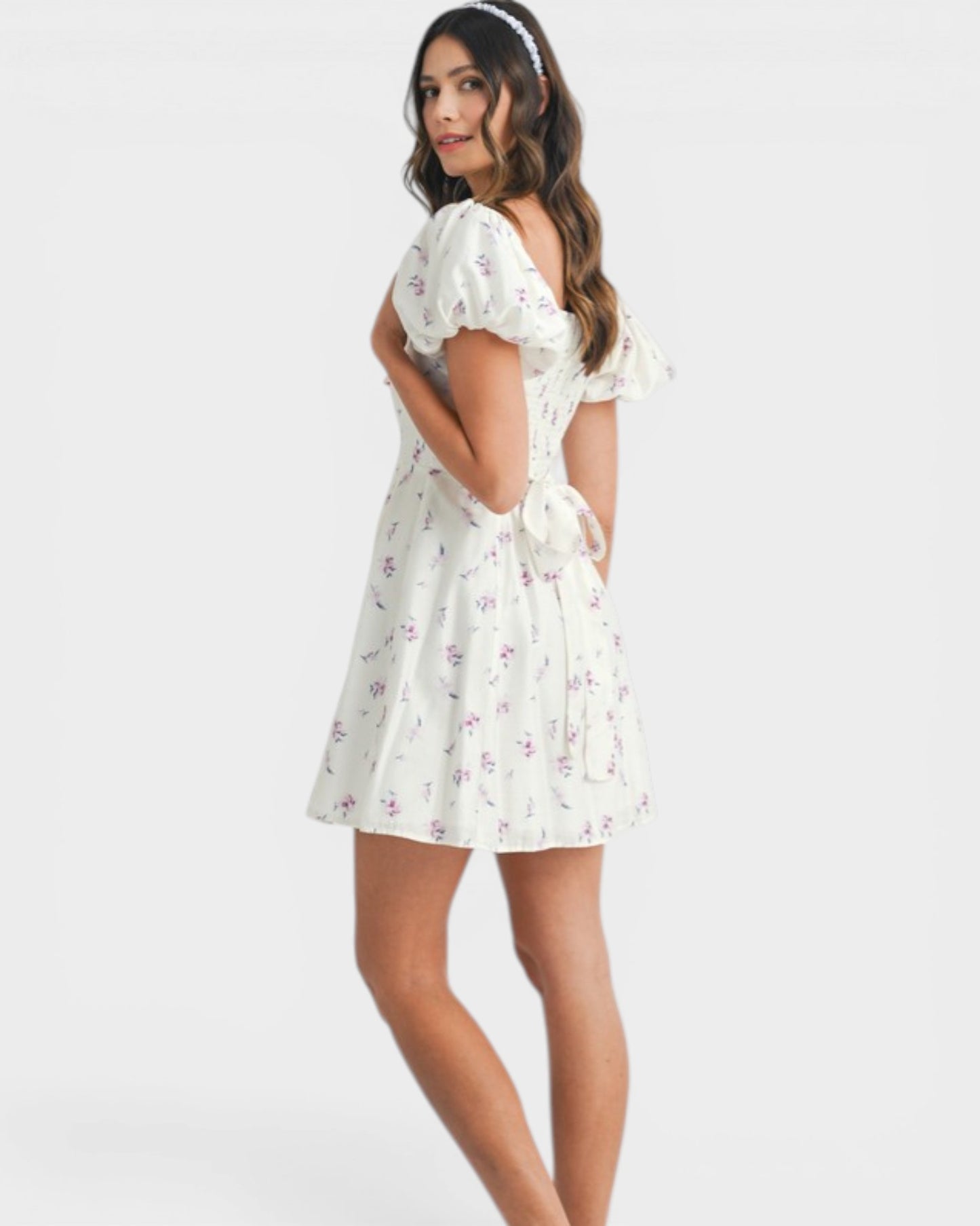 Woman wearing a white floral dress on a plain background
