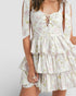 Woman wearing a white floral dress with a plain background