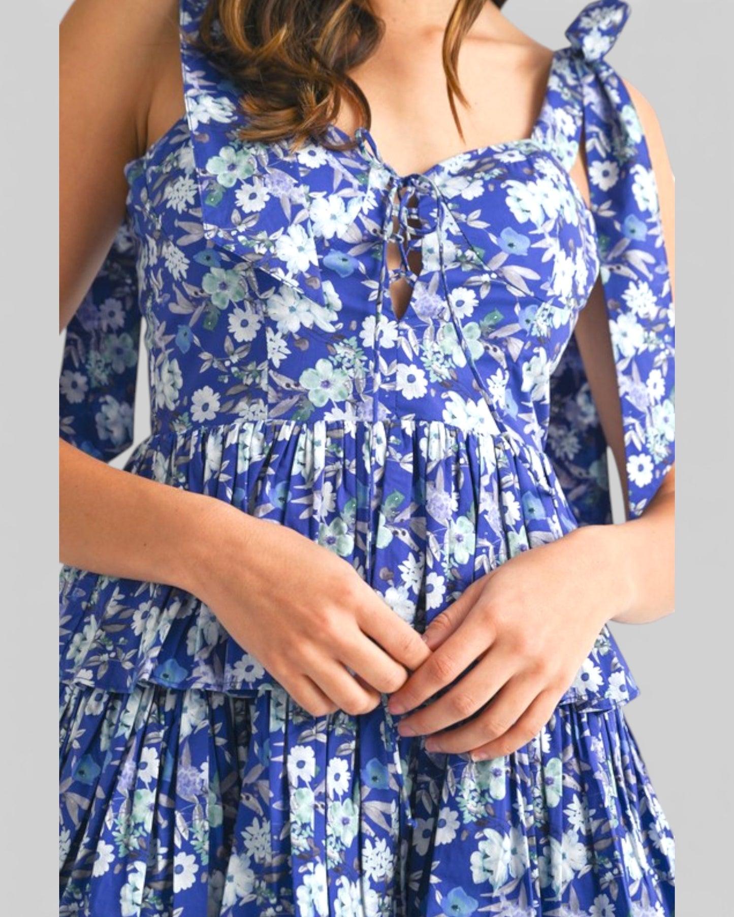 Blue floral dress worn by a person on a gray background