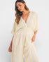 Woman wearing a cream-colored jumpsuit against a white background