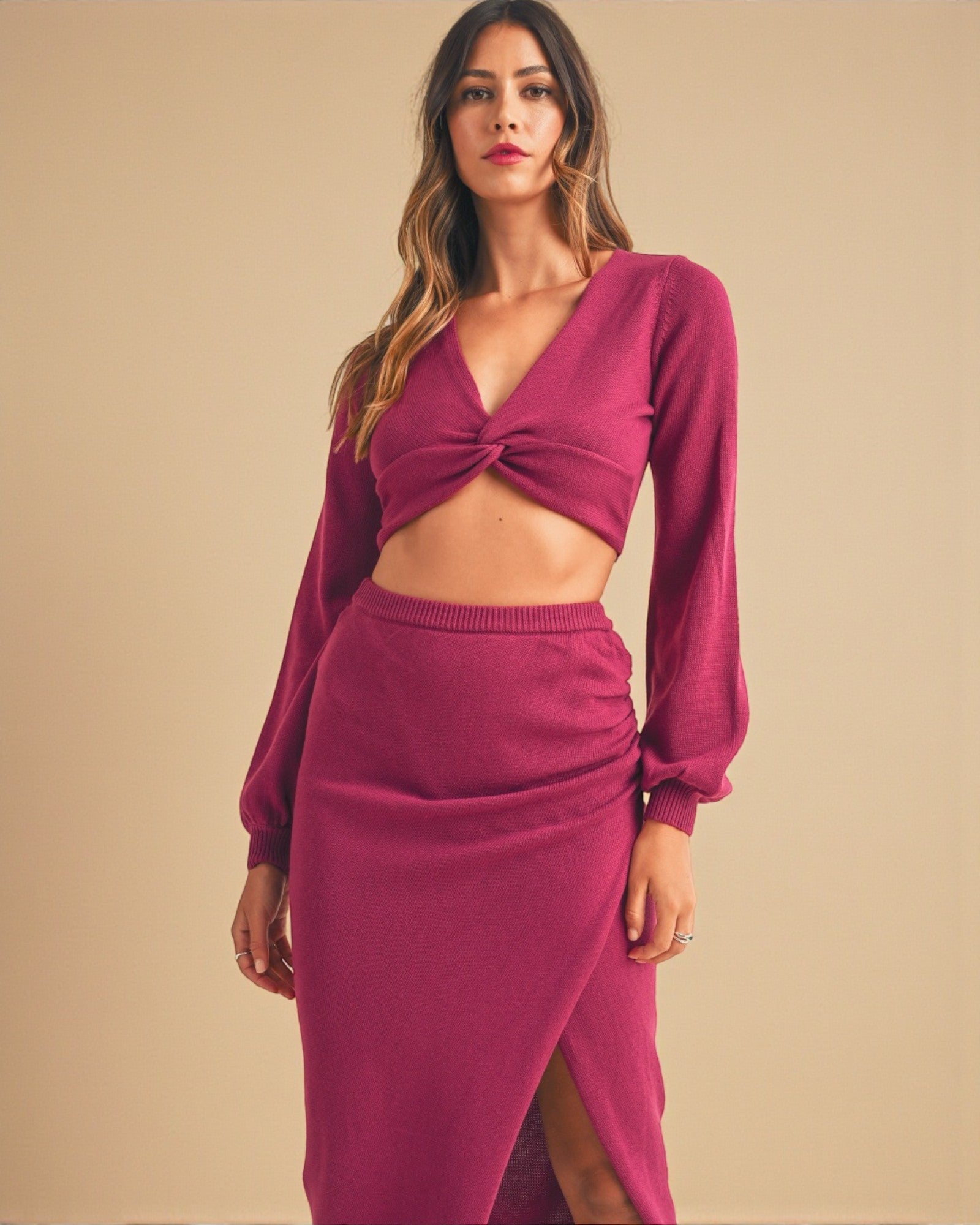 Woman wearing a maroon outfit with a top and skirt on a beige background