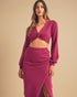 Woman wearing a maroon outfit with a top and skirt on a beige background