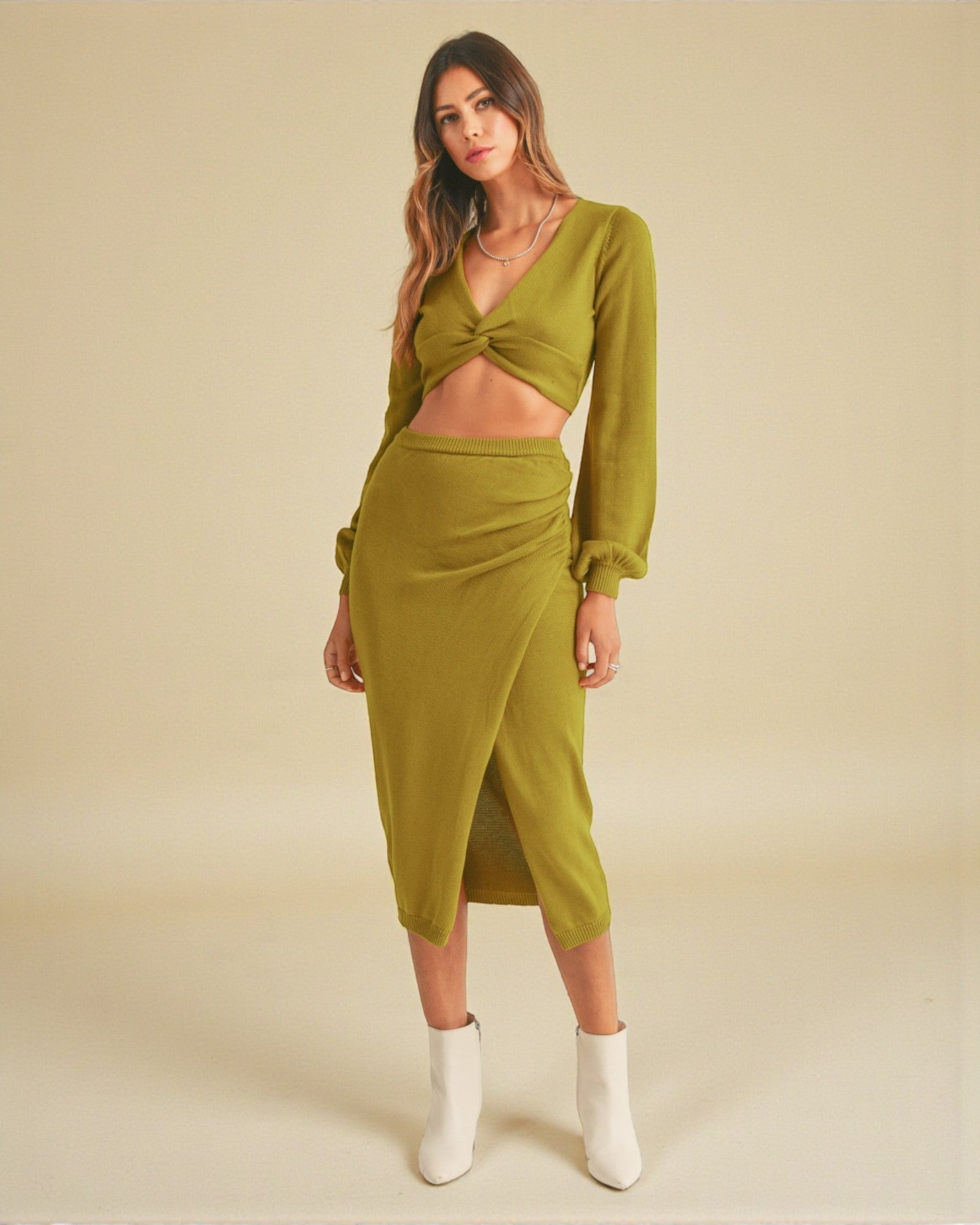 Woman wearing a green outfit with a top and skirt on a beige background
