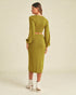 Woman wearing a green dress with long sleeves on a beige background