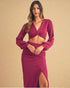 Woman wearing a burgundy outfit with a top and skirt on a beige background