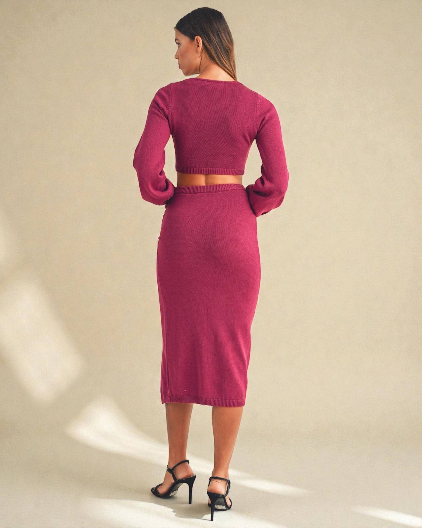 Woman wearing a magenta two-piece outfit against a beige background