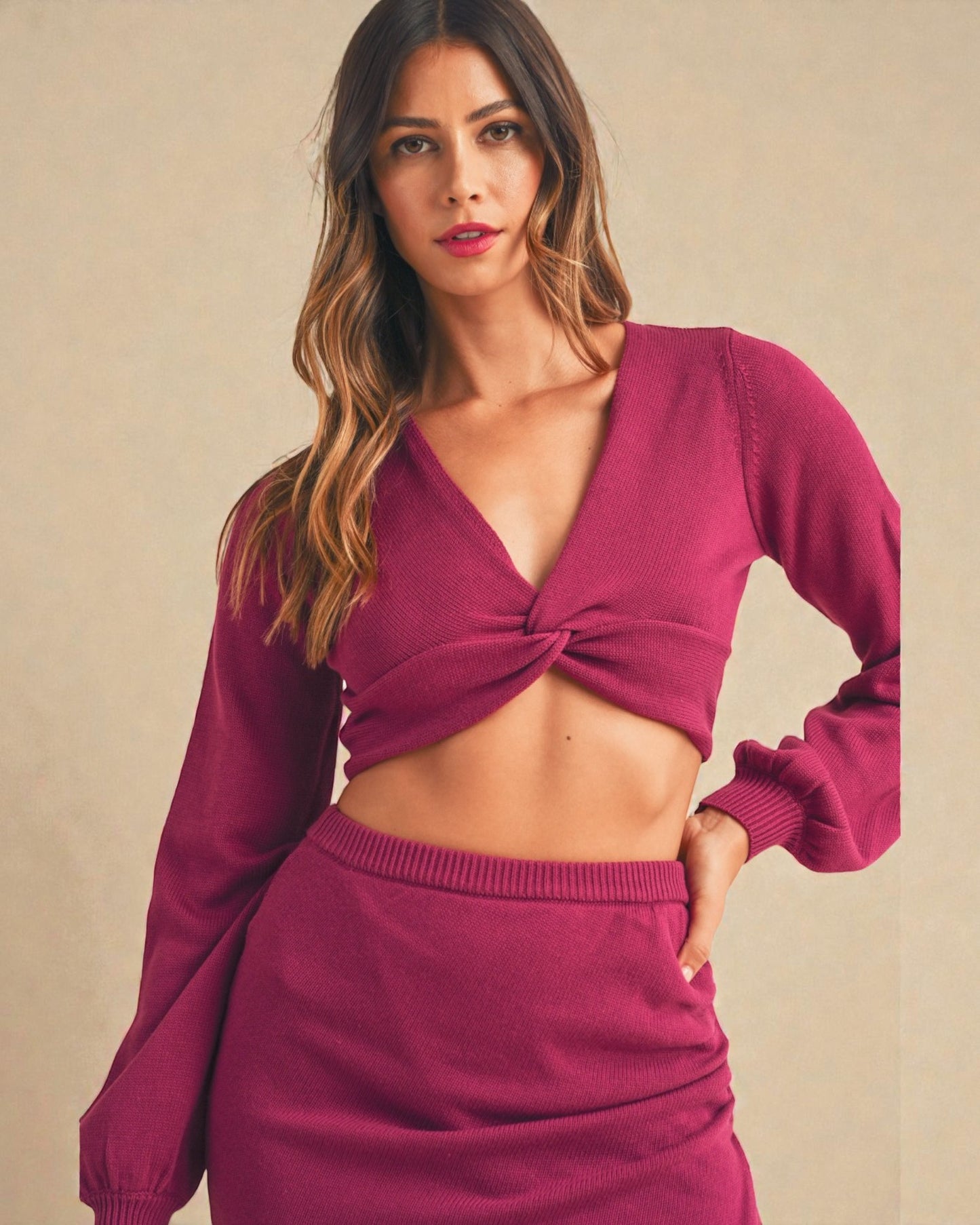 Woman wearing a maroon long-sleeve top and skirt set against a beige background