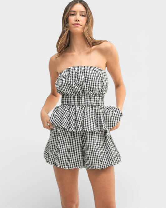 Woman wearing a black and white checkered strapless romper on a light gray background
