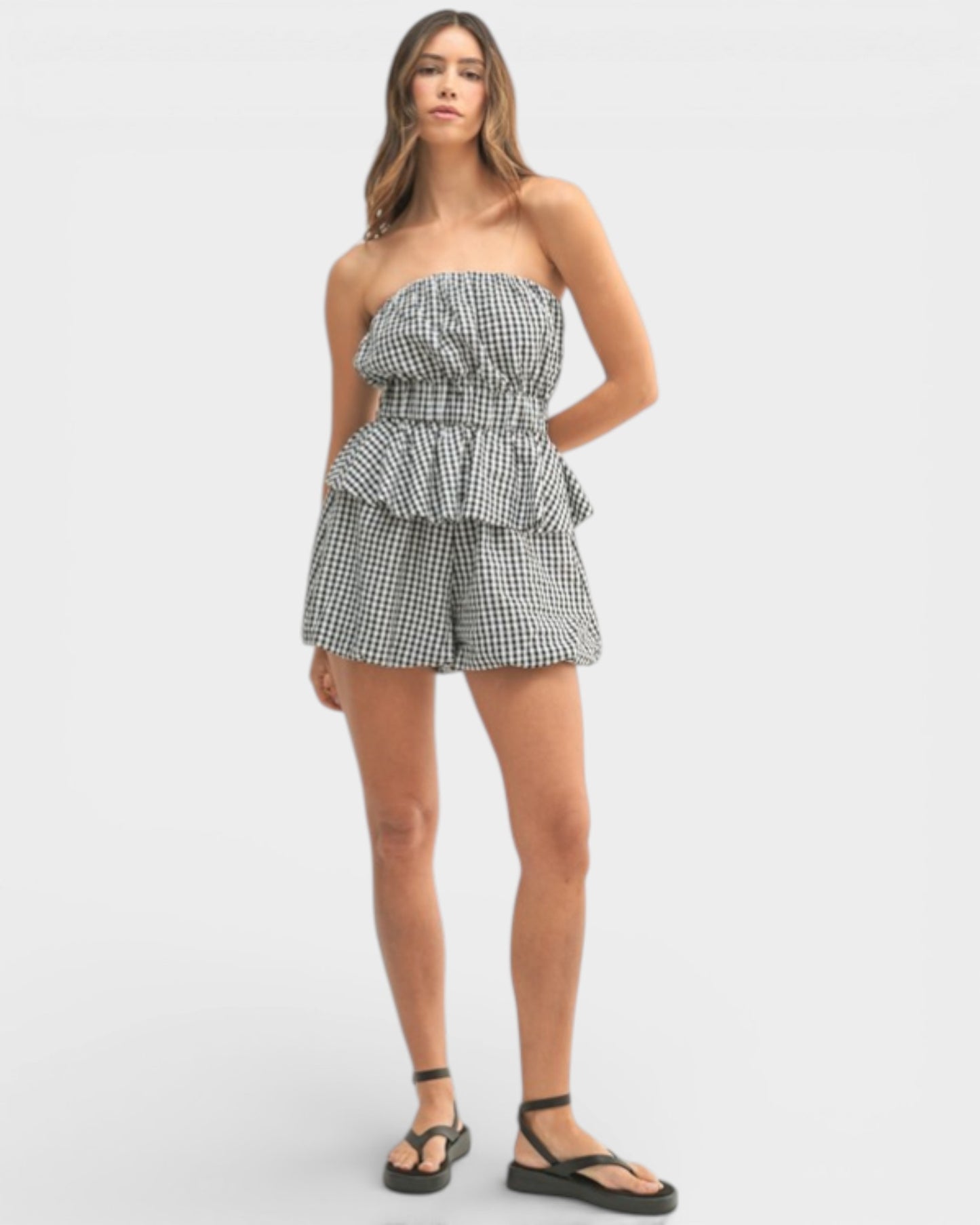 Woman wearing a strapless checkered romper on a white background