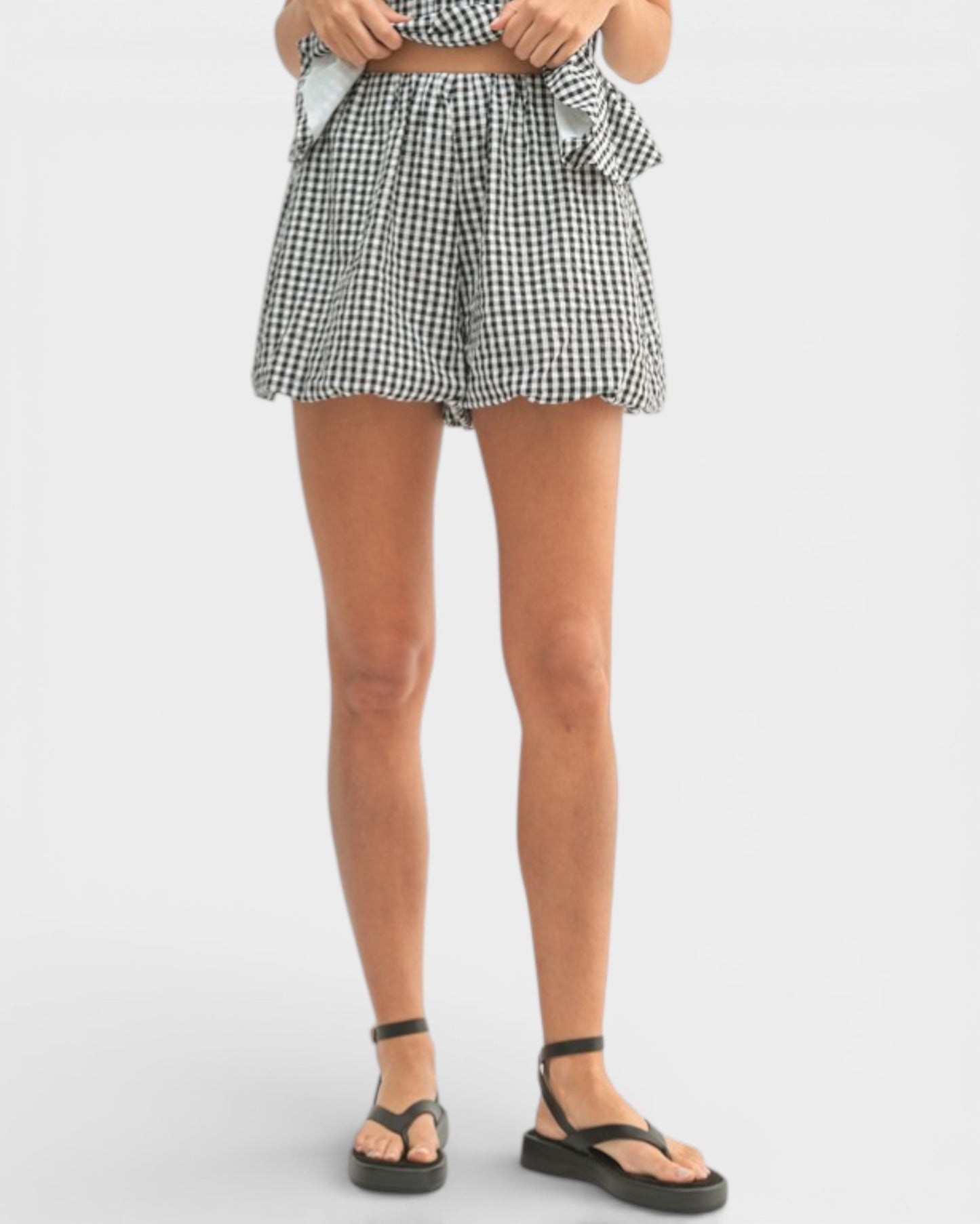Person wearing black and white checkered shorts on a white background