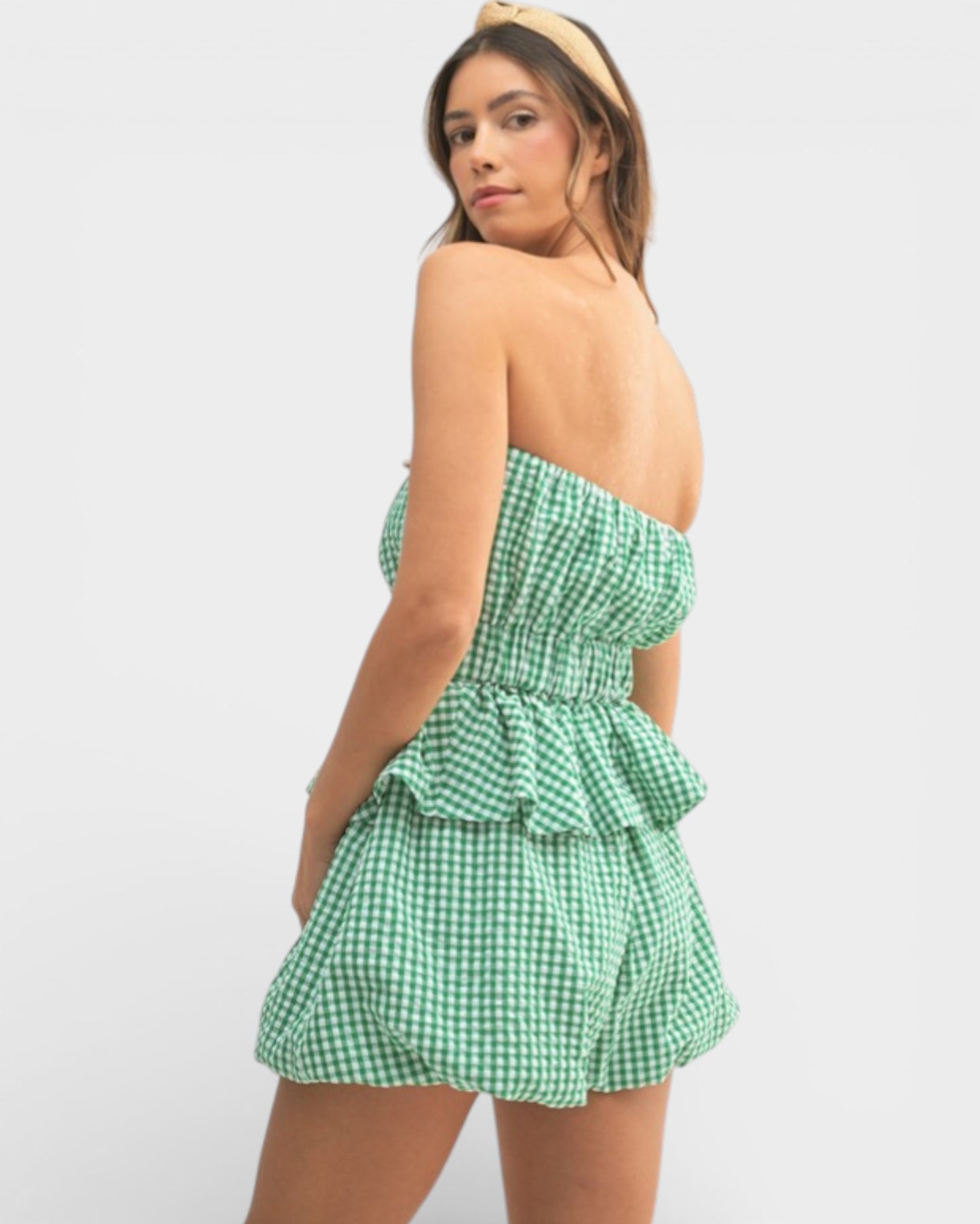 Woman wearing a green checkered strapless dress on a white background