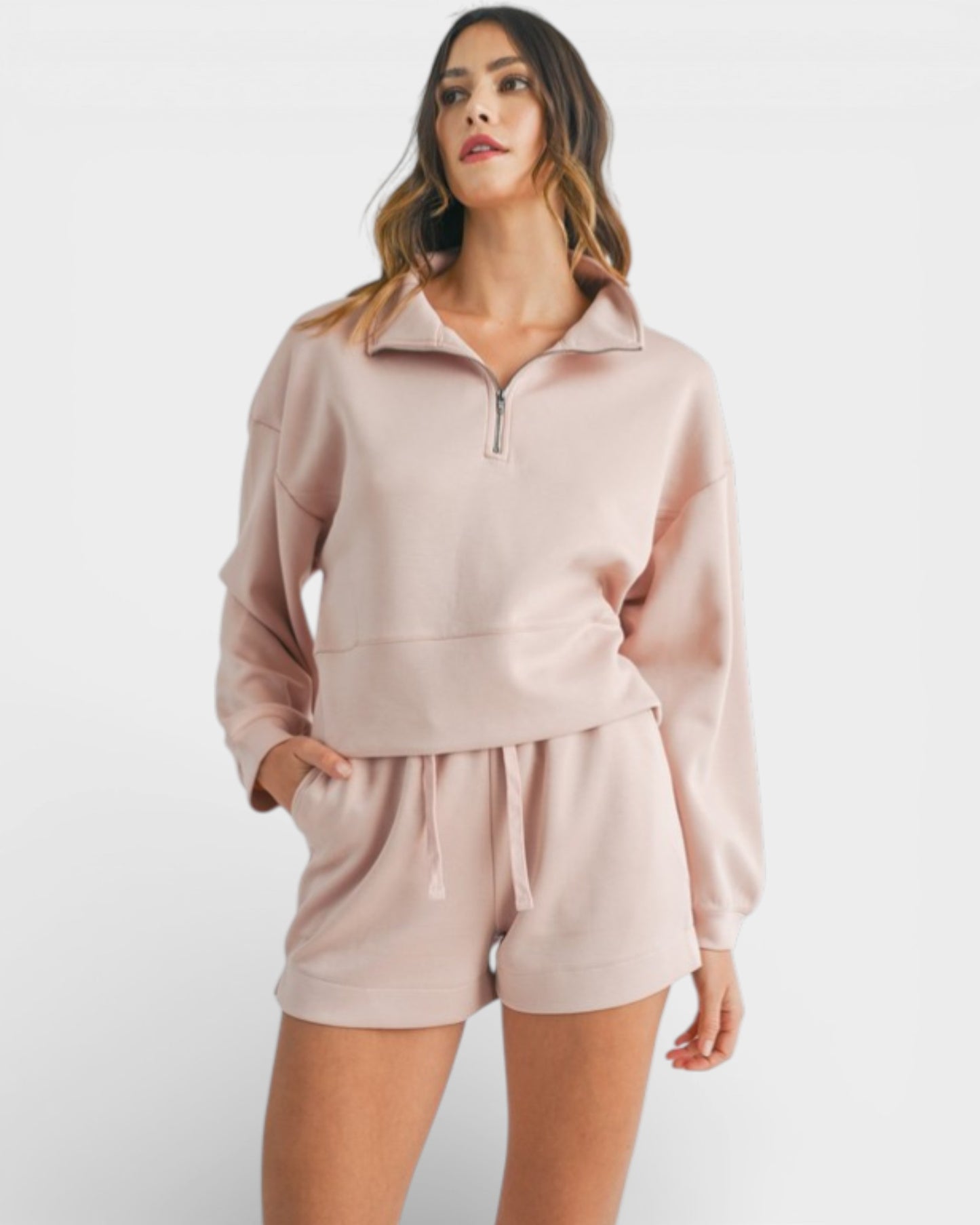 Woman wearing a light pink tracksuit on a white background