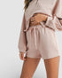 Person wearing a matching pink sweatshirt and shorts set on a white background