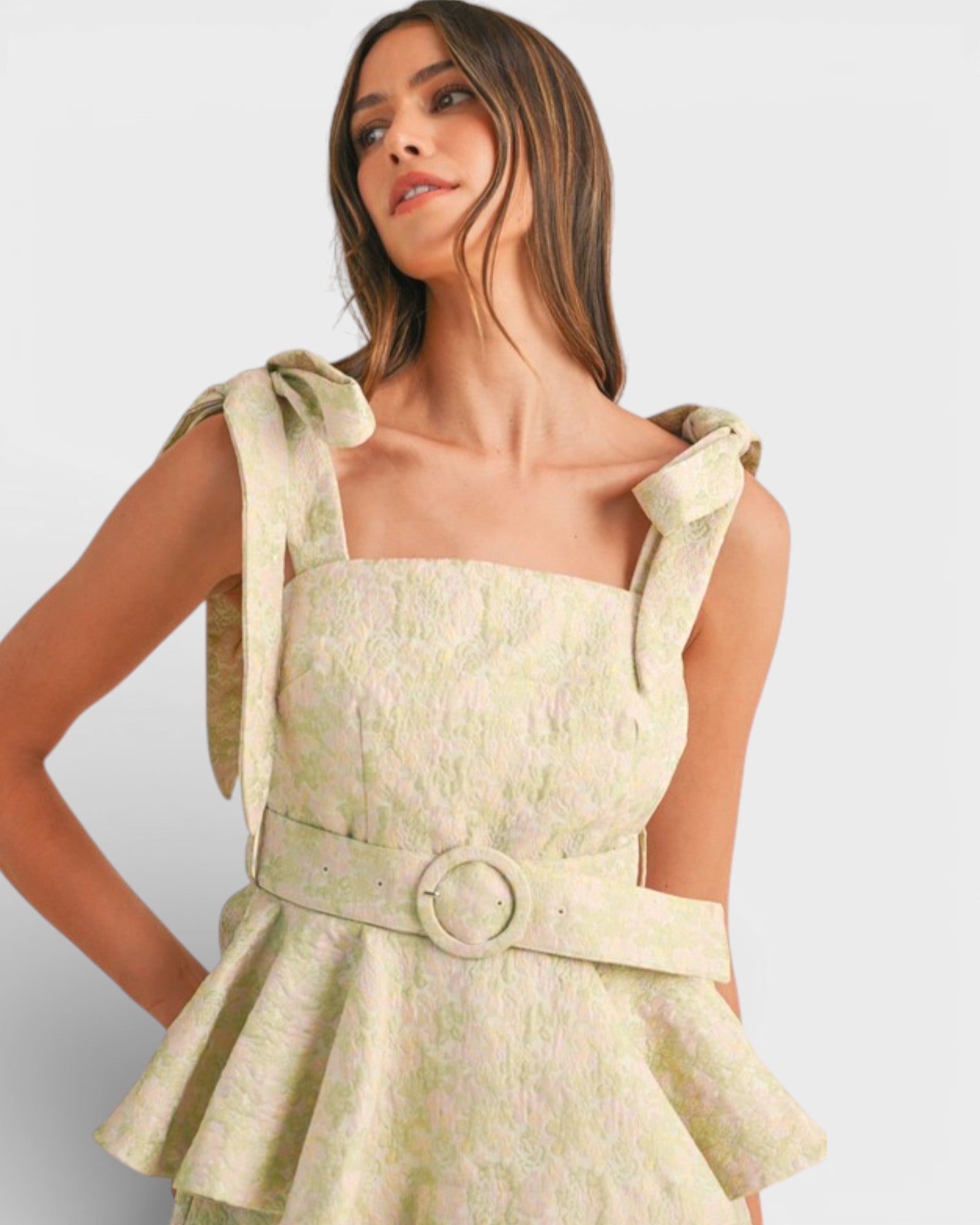 Woman wearing a light green dress with bow straps on a white background
