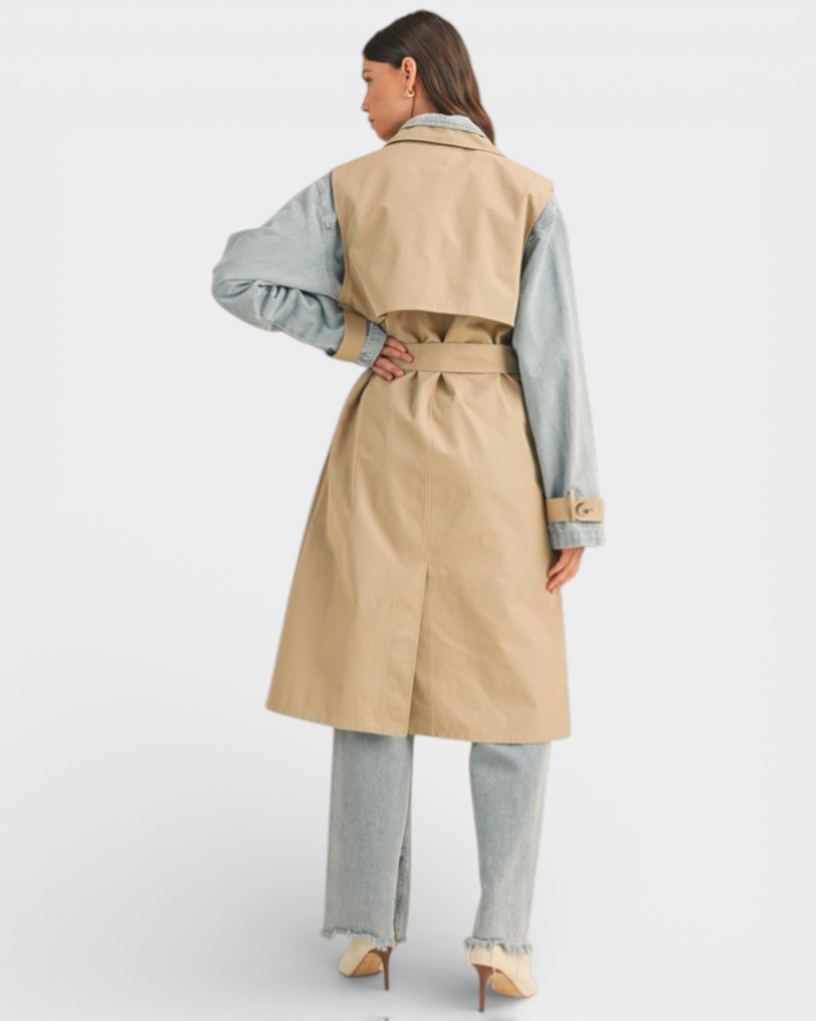 Woman wearing a beige trench coat over a light blue shirt on a white background