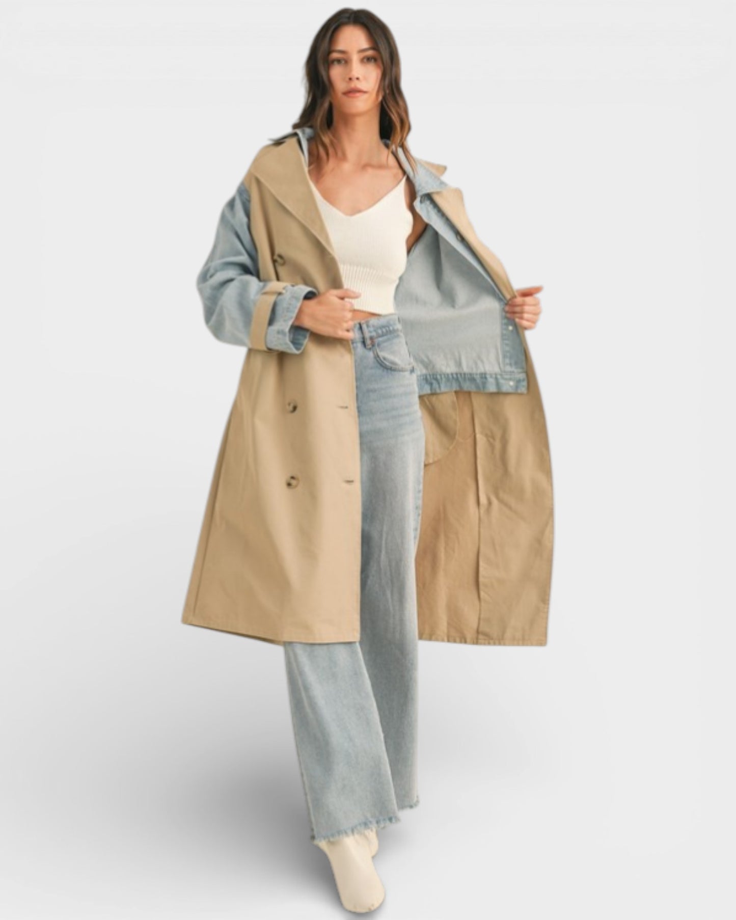Woman wearing a beige trench coat with color-blocked sleeves on a white background