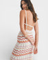 Woman wearing a colorful zigzag patterned dress with open back on a white background