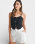 Woman wearing a black top and white shorts on a plain background