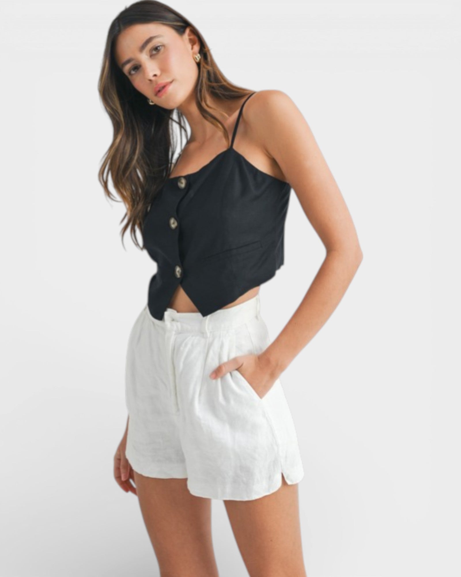Woman wearing a black top and white shorts on a light gray background