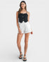 Woman wearing a black top and white shorts on a white background