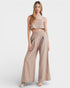 Woman wearing a beige sleeveless top and wide-leg pants on a white background