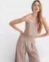 Woman wearing a beige top and pants against a white background