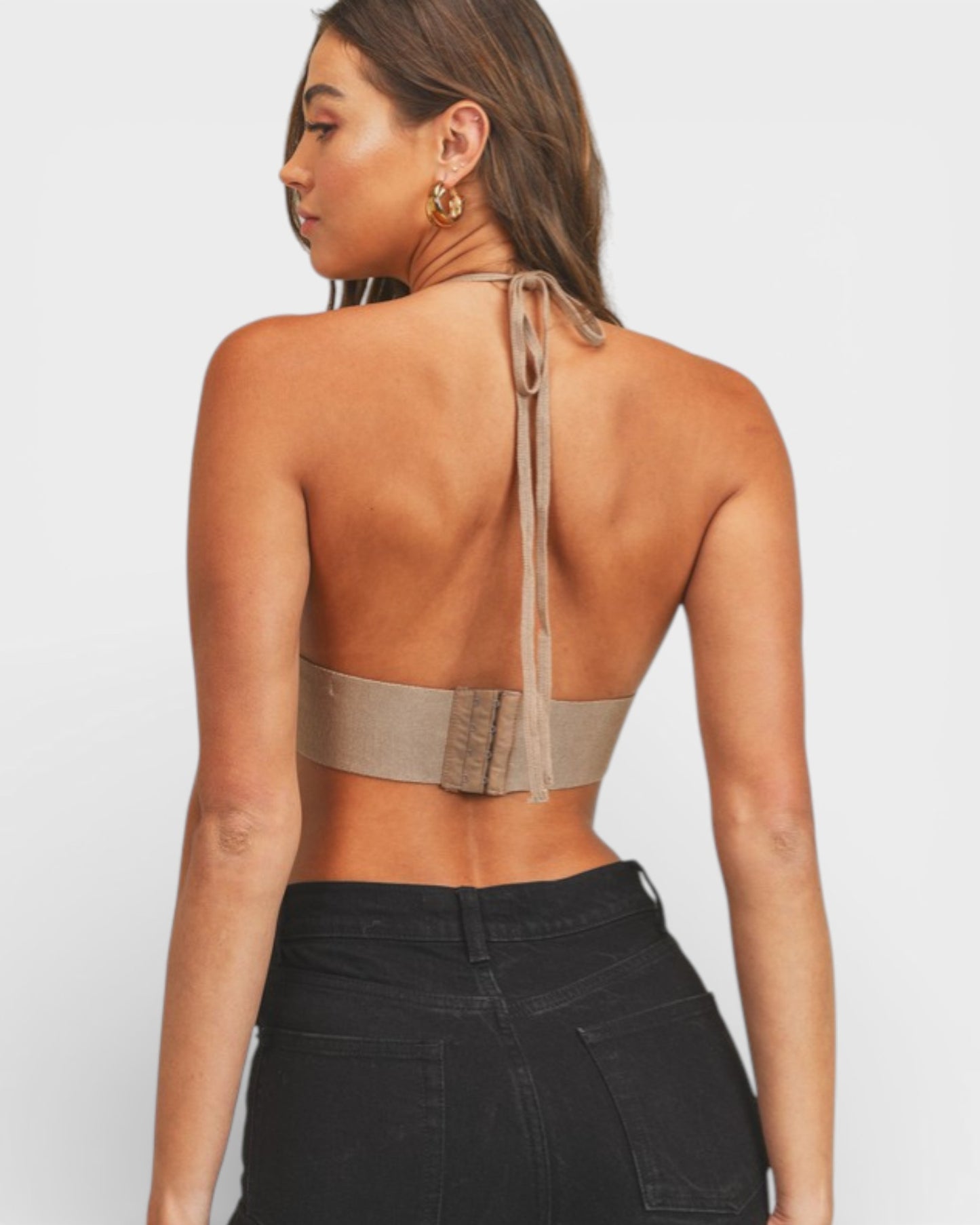 Woman wearing a beige halter top with thin straps on a white background