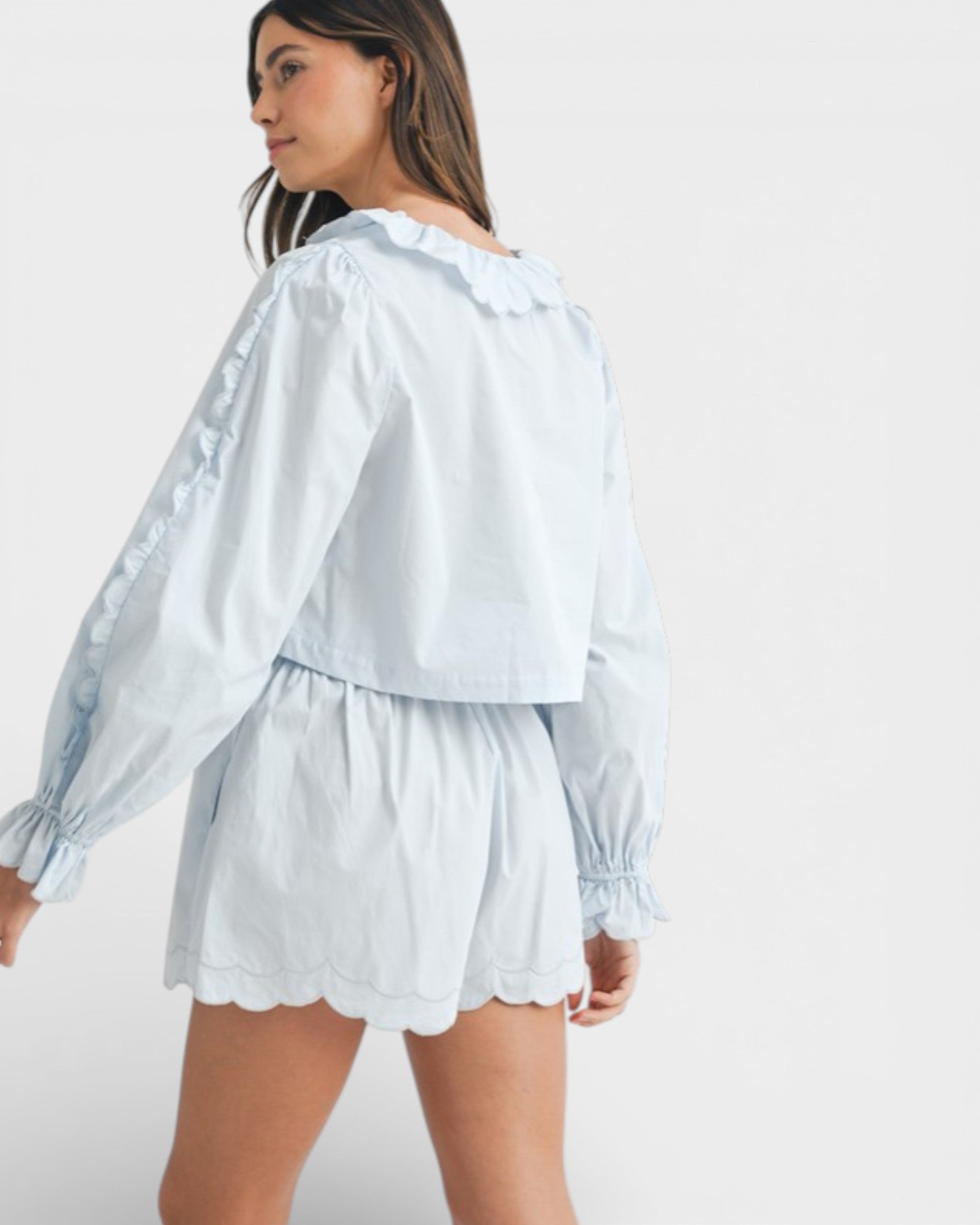 Woman wearing a light blue blouse and shorts set on a white background