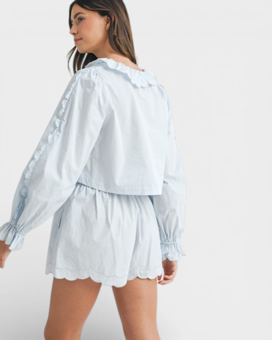 Woman wearing a light blue blouse and shorts set on a white background