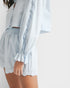 Light blue outfit with ruffled sleeves on a plain background