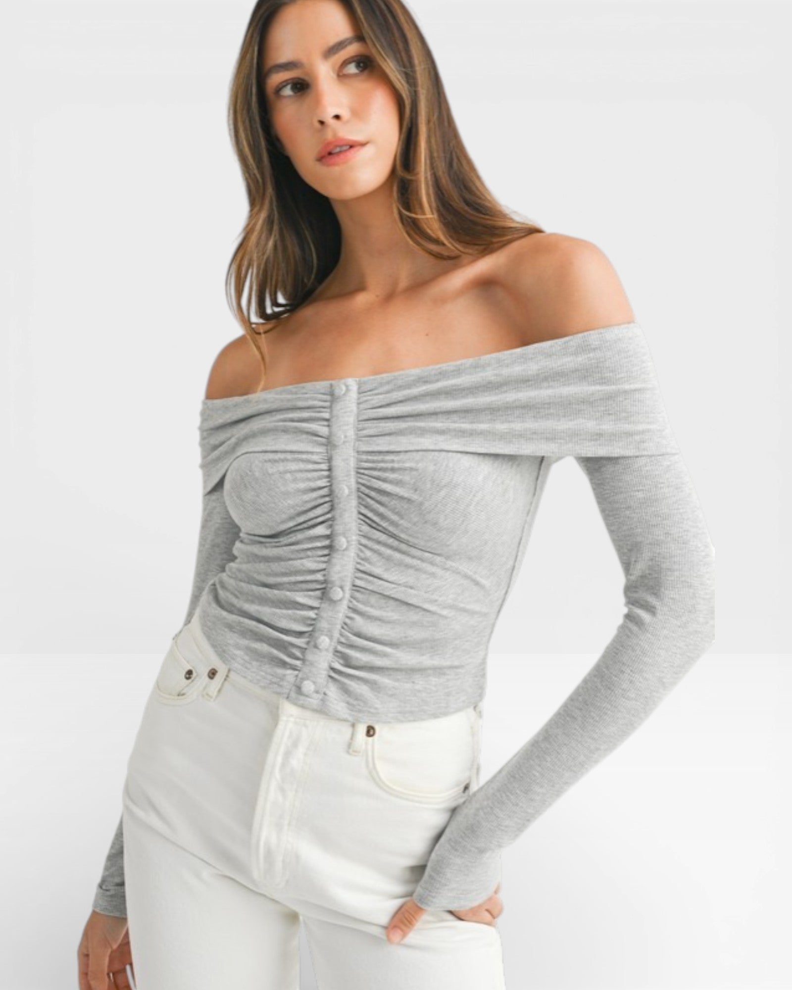 Woman wearing a gray off-shoulder top and white pants on a white background