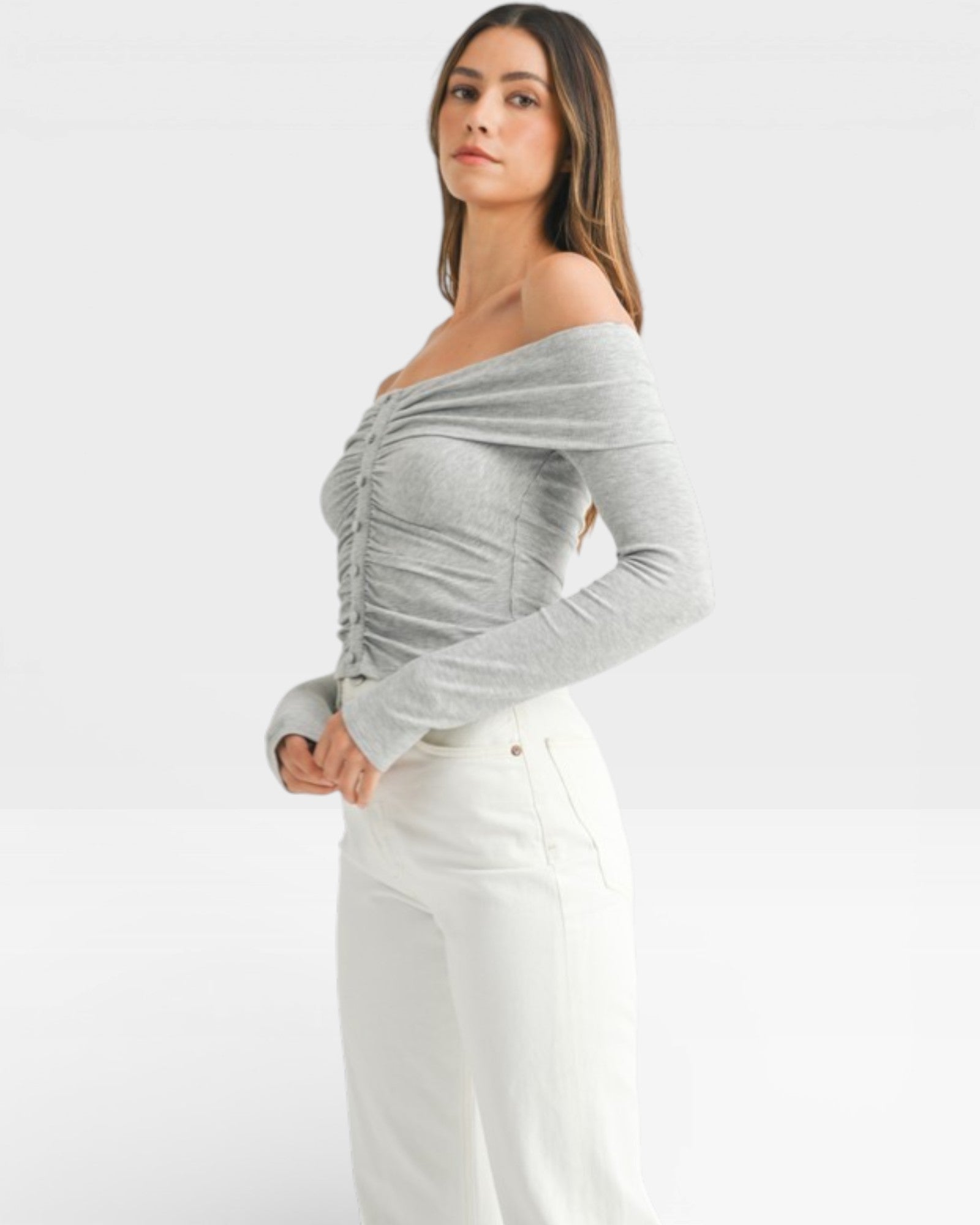 Woman wearing a gray off-shoulder top and white pants on a white background