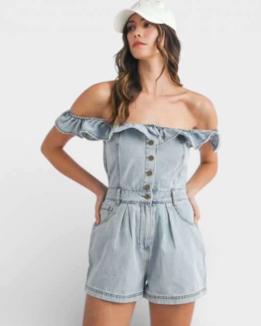 Woman wearing a light blue denim romper with a white cap on a white background