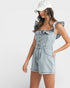 Woman wearing a denim romper with ruffled straps on a white background