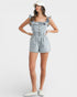 Woman wearing a denim romper with ruffled straps on a white background