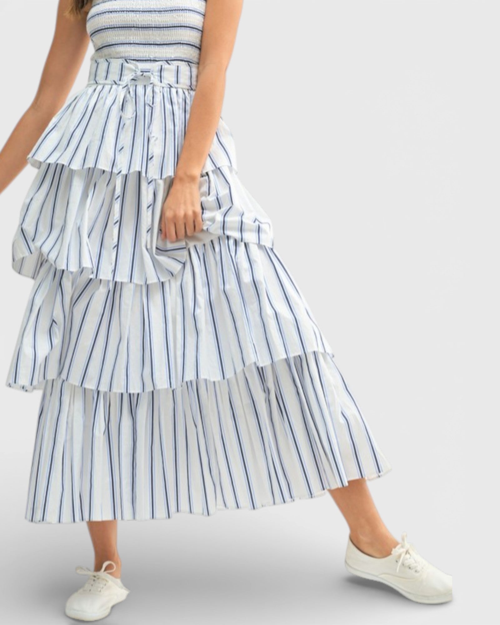 Person wearing a blue and white striped tiered skirt on a light gray background