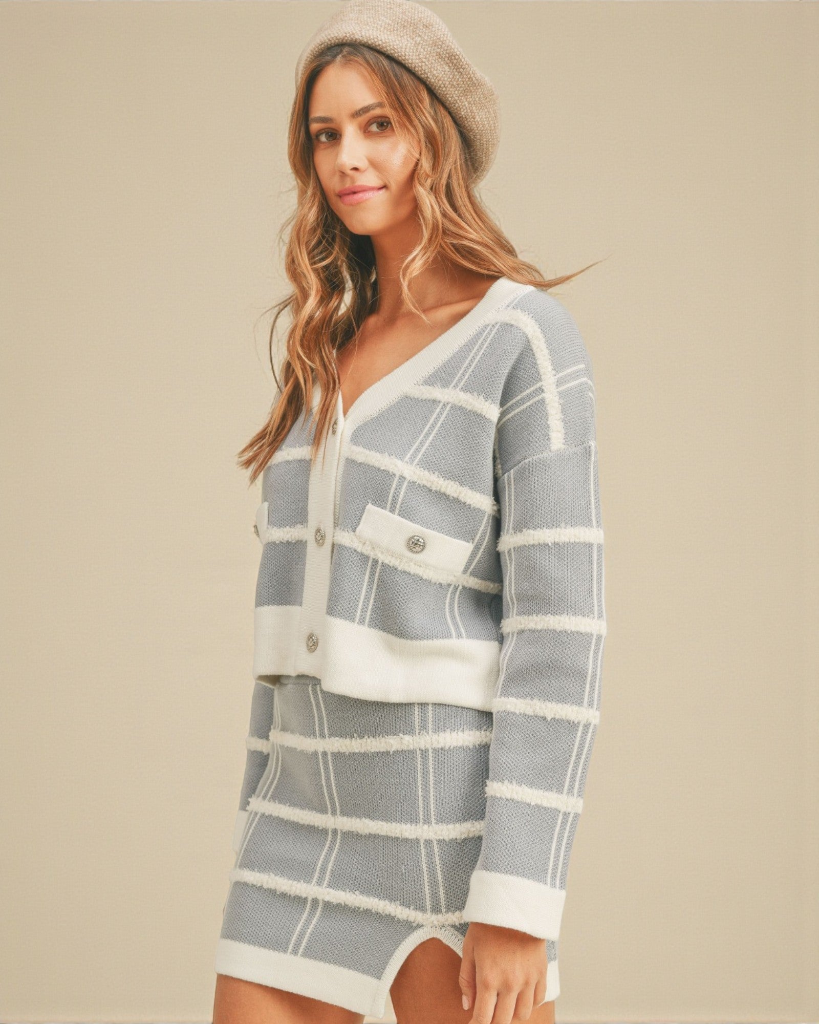 Woman wearing a gray and white striped sweater dress with a beige background